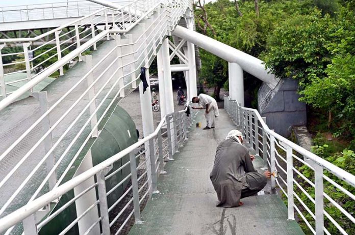 Workers busy painting a pedestrian bridge at Expressway in the Federal Capital
