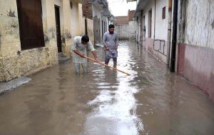 People passing through rainwater accumulated in the street after heavy rain in Provincial Capital.