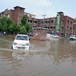 A vehicle passing through rainwater accumulated at Divisional Headquarter Shahbaz Building after heavy rain in the city