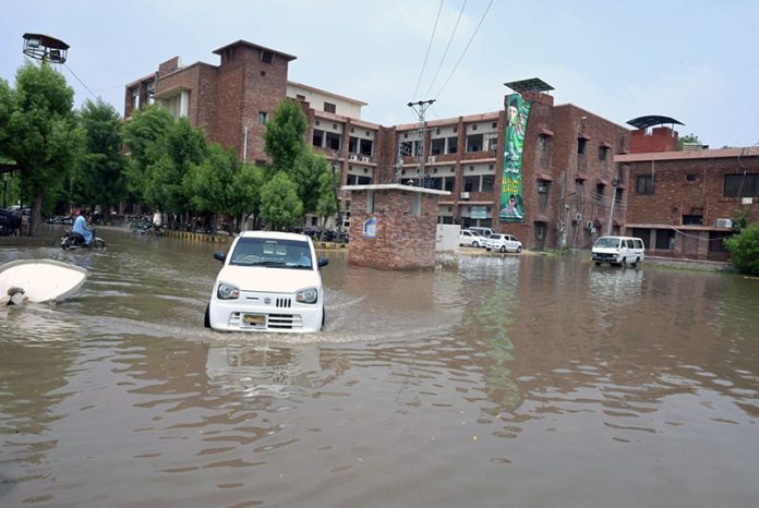 A vehicle passing through rainwater accumulated at Divisional Headquarter Shahbaz Building after heavy rain in the city