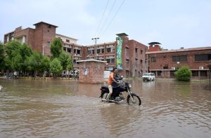 A vehicle passing through rainwater accumulated at Divisional Headquarter Shahbaz Building after heavy rain in the city