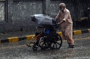 A motorcyclist balances his ride with an umbrella in hand to shield himself from heavy rainfall while passing through the city.