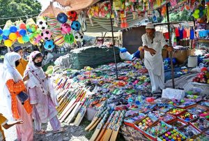 A family purchasing toys from an elderly vendor’s stall at I-9/4 bazaar in the Federal Capital.