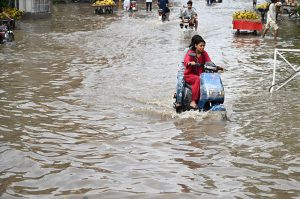 Vehicles pass through accumulated rainwater on a road during rainfall in the provincial capital