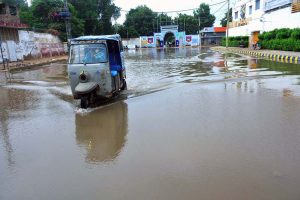 A vehicle passing through rainwater accumulated at Divisional Headquarter Shahbaz Building after heavy rain in the city