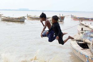 Children diving into the Indus River for swimming after rising water levels caused by heavy monsoon rains. Experts advise caution to avoid any mishap.