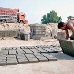 A worker is busy making and spreading tuff tiles for drying at his workplace