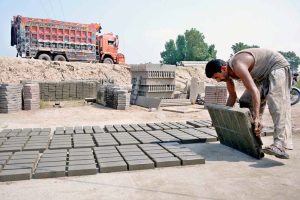 A worker is busy making and spreading tuff tiles for drying at his workplace