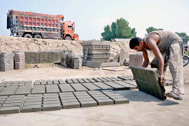 A worker is busy making and spreading tuff tiles for drying at his workplace