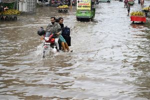 Vehicles pass through accumulated rainwater on a road during rainfall in the provincial capital