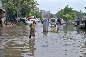 A vehicle passing through rainwater accumulated at Divisional Headquarter Shahbaz Building after heavy rain in the city