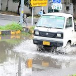 A vehicle passing through rain water accumulated on road after rain in the federal capital
