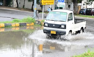 A vehicle passing through rain water accumulated on road after rain in the federal capital