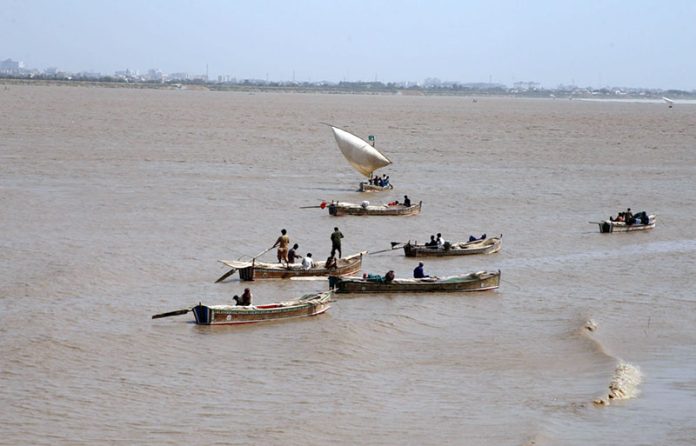 Fishermen catching the fish on their boats after rising water level in Indus river at kotri barrage, caused by ongoing heavy monsoon rains across the country
