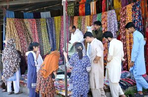 A family purchasing toys from an elderly vendor’s stall at I-9/4 bazaar in the Federal Capital.