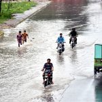 Vehicles passing through stagnant rainwater on a road after heavy rainfall in the Provincial Capital 