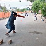 Youngsters playing cricket on the road at Azadi Chowk