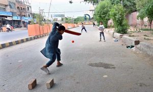 Youngsters playing cricket on the road at Azadi Chowk