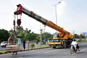 Labourers sitting in the pocket of a loader crane while heading to a worksite on Walton Road