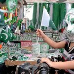 A child wearing a mask purchasing Independence Day celebration items in the Saddar area