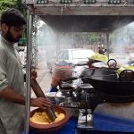 A street vendor prepares and sells traditional fresh laddoo on his handcart
