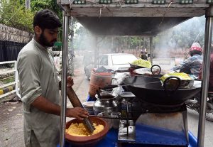A street vendor prepares and sells traditional fresh laddoo on his handcart