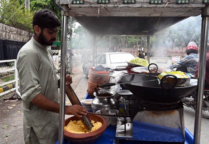 A street vendor prepares and sells traditional fresh laddoo on his handcart