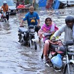 Motorcyclists are wades through floodwaters at Jail Road after heavy rainfall in the city