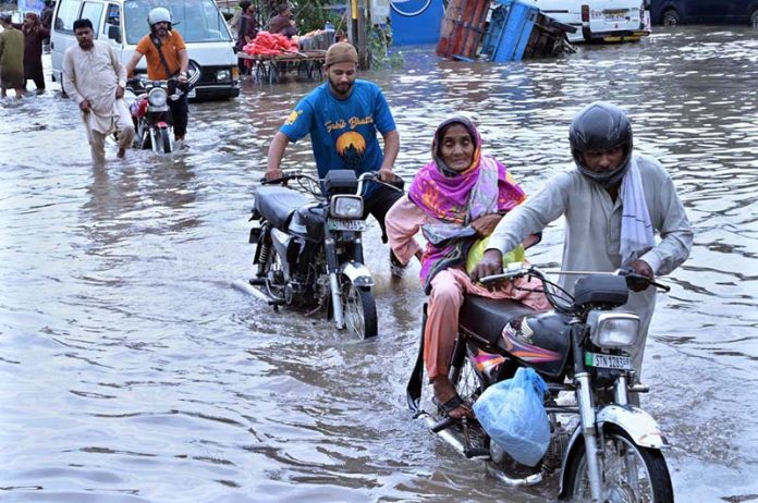 Motorcyclists are wades through floodwaters at Jail Road after heavy rainfall in the city