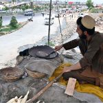 A vendor busy in roasting corn cobs to attract customers at his roadside setup