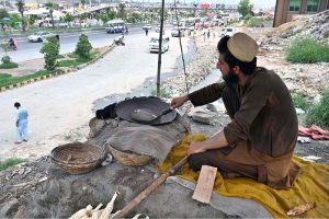 A vendor busy in roasting corn cobs to attract customers at his roadside setup