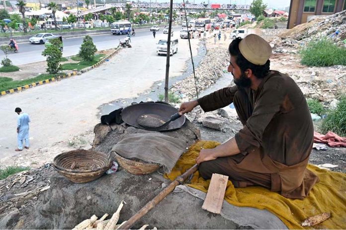 A vendor busy in roasting corn cobs to attract customers at his roadside setup