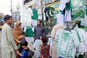 A child wearing a mask purchasing Independence Day celebration items in the Saddar area