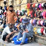 Customers purchasing caps from a vendor at a roadside stall.