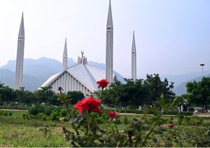 A beautiful view of Faisal Mosque with blooming roses in the foreground after rainfall in the federal capital