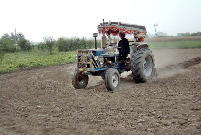 A farmer busy preparing land for next crop with help of tractor at Lahore Road