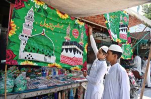 Youngsters displaying flags and badges at a roadside stall in connection with Rabi-ul-Awal celebrations.