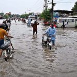 A large number of people are passing through floodwaters at Jail Road after heavy rainfall in the city
