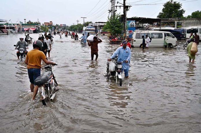 A large number of people are passing through floodwaters at Jail Road after heavy rainfall in the city
