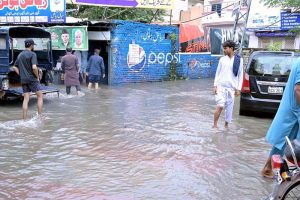 A large number of people are passing through floodwaters at Jail Road after heavy rainfall in the city