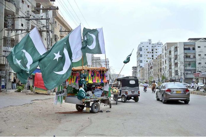 A vendor displaying national flags and another items at Gulshan-e-Sajjad Road to attract the customers in connection with upcoming 78th Independence Day celebration of Pakistan