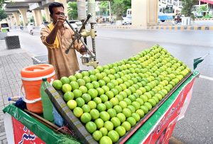 A street vendor prepares fresh sweet lime juice for a customer at his roadside stall.
