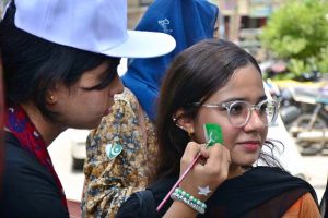 Students from the University of Arts, Design and Heritage painting national flags on each other's faces during a rally for Jashan-e-Marka-e-Haq and Independence Day in connection with upcoming 78th Independence Day celebrations outside Press Club.