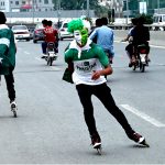 Youngsters having costumes in the colors of national flag of Pakistan skating on the roads to celebrate the 78th Independence Day of Pakistan in the city