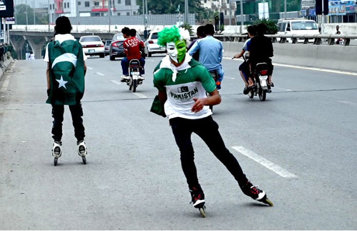 Youngsters having costumes in the colors of national flag of Pakistan skating on the roads to celebrate the 78th Independence Day of Pakistan in the city