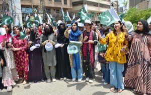 Students from the University of Arts, Design and Heritage painting national flags on each other's faces during a rally for Jashan-e-Marka-e-Haq and Independence Day in connection with upcoming 78th Independence Day celebrations outside Press Club.