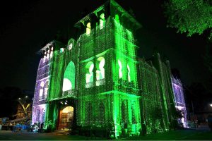 An illuminated view of Wapda House building adorned with Pakistani flag lights in connection with Independence Day celebrations