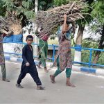 Village women carrying tree branches on their heads for domestic use while walking along Jamshoro Road