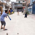 Youngsters enjoy playing cricket in a street