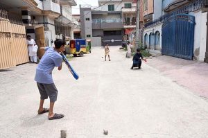 Youngsters enjoy playing cricket in a street